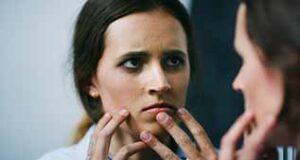 Il faut repérer la dysmorphophobie en consultation d’esthétique femme anxieuse regardant son visage dans un miroir