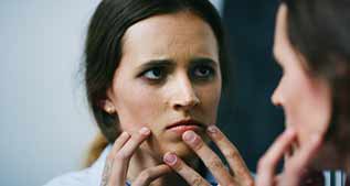 Il faut repérer la dysmorphophobie en consultation d’esthétique femme anxieuse regardant son visage dans un miroir